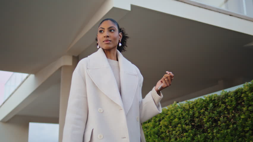 Confident woman walking street suburbs. Gorgeous african american realtor hold keys stroll neighborhood. Stylish businesswoman commute home in evening. Real estate agent landlord go to client meeting | Shutterstock HD Video #1101016181