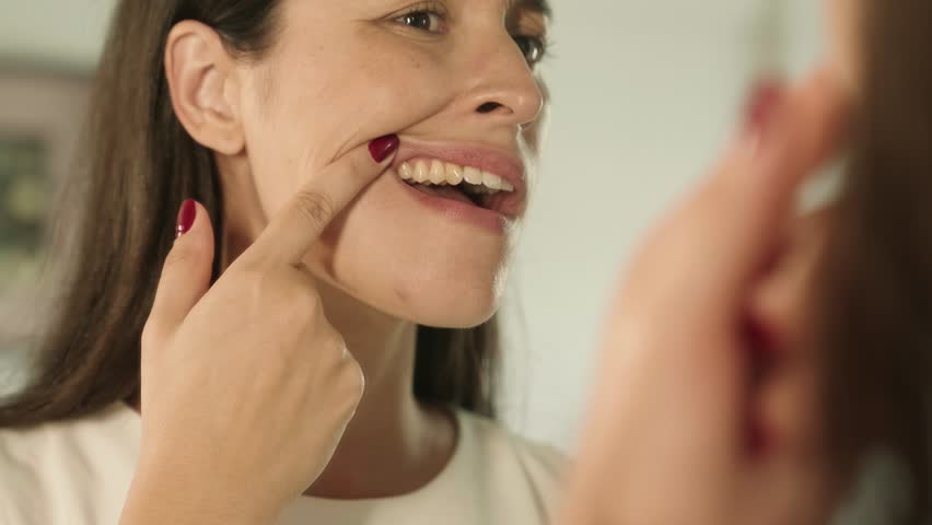 Woman checking her teeth in mirror with opened mouth looking for caries in bathroom at home. Teeth health care concept.
 Royalty-Free Stock Footage #1101017427