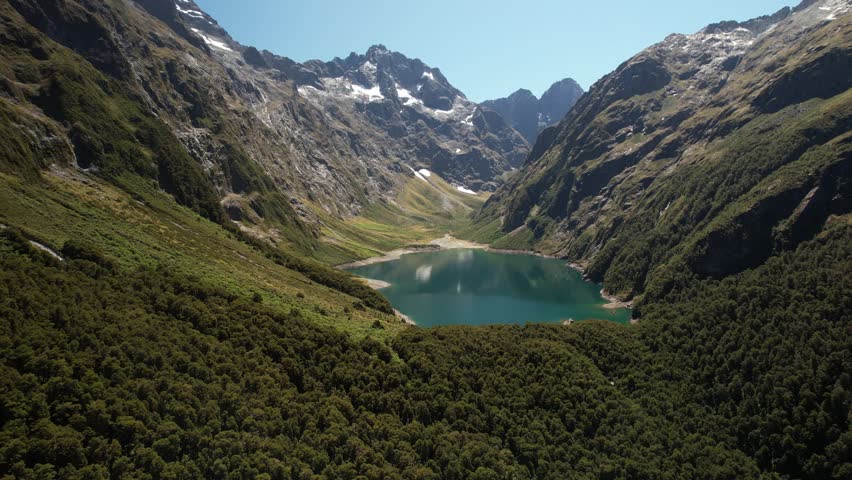 Beautiful Lake Marian surrounded by high mountain peaks, Fiordland National park, New Zealand. Drone pull back Royalty-Free Stock Footage #1101017639