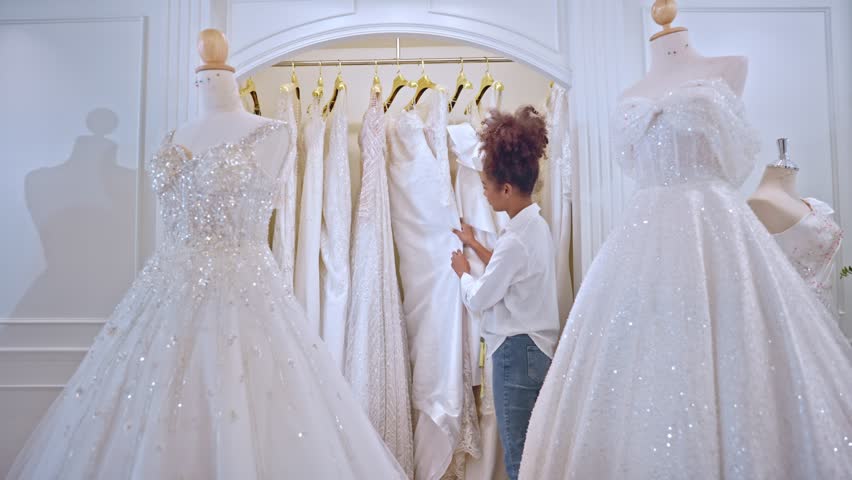 African American female designer designing bridal gown in wedding studio. Attractive young woman tailor dressmaker working and enjoy making new pattern collection of dress in fitting room at the store Royalty-Free Stock Footage #1101021619