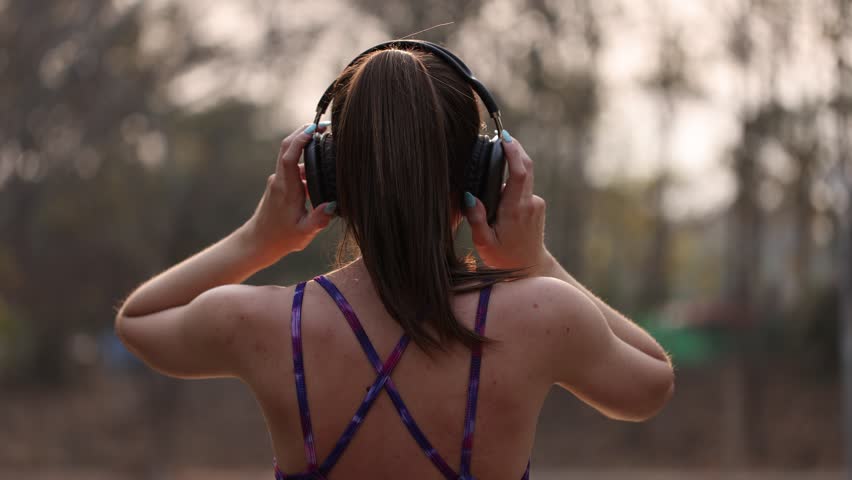 Woman exercising and wearing headphones in nature.
