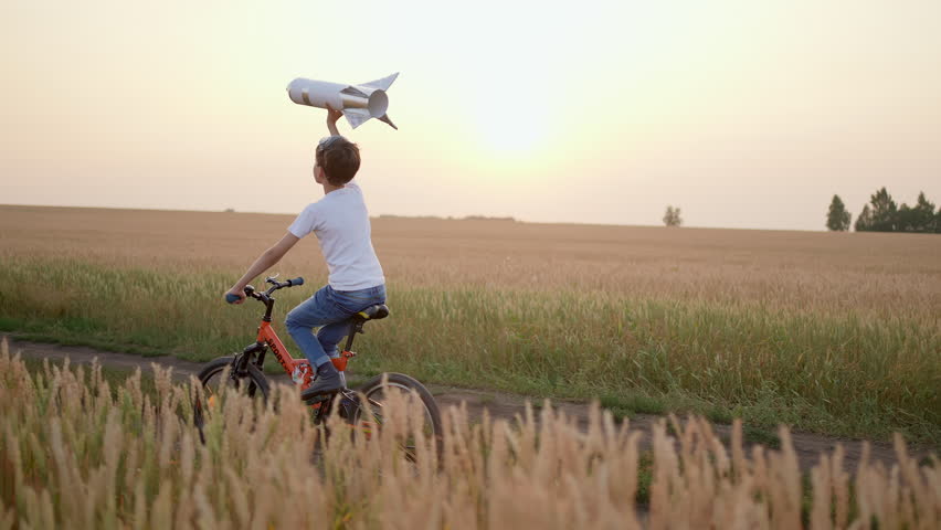 Little happy boy child teenager aviator cosmonaut riding bike with toy rocket in sunset field summer nature. Kid big dream flying, astronaut, space. Concept of success winner travel freedom childhood  Royalty-Free Stock Footage #1101025263