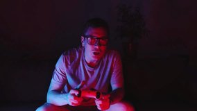 Mid adult man sitting on sofa and playing video games with controller. Neon lightning e-sport concept