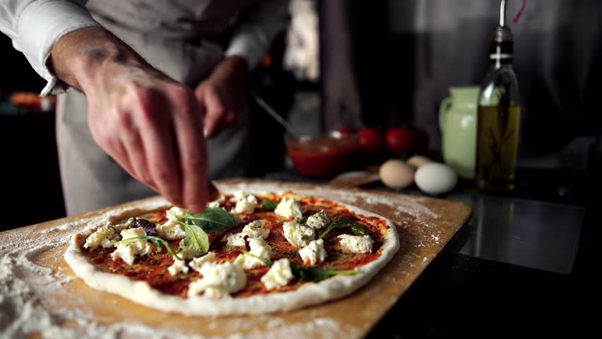 Pizzaiolo Chef Cooking Italian Pizza Making. Seasoning Oregano In Pizza. Pizzaiolo Making Pizza Margherita Seasoning Dry Basil And Oregano. Chef Cooking Tasty Margherita Pizza In Italian Restaurant