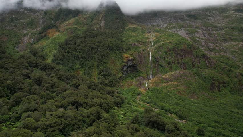 Beautiful waterfall from high mountain in Fiordland National Park, New Zealand - drone