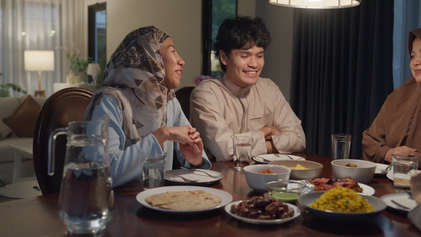 Happy Asia muslim parent and their kids Ramadan dinner together in dining room at home. Family of two generation catering celebration end of Eid al-Fitr togetherness at home. Hari Raya family reunion. Royalty-Free Stock Footage #1101033725