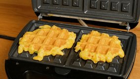 Cooked homemade vegetable pumpkin waffles are taken from electric waffle maker. Vegetarian eating. Breakfast concept. 4k footage.