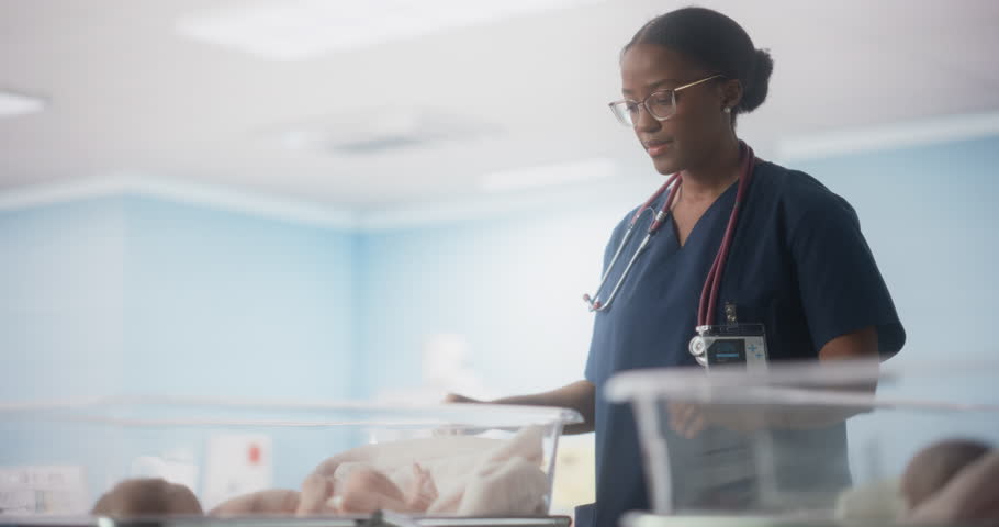 Cute Emotional Newborn Little Infant Lying in Hospital Cot. Young Black Pediatrician Taking Care of the Baby and Fixing the Blanket. Healthcare, Pregnancy and Motherhood Concept