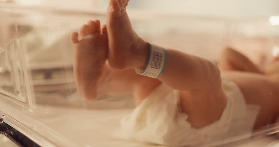 Cute Little Caucasian Newborn Baby Lying in Bassinet in a Maternity Hospital. Portrait of a Tiny Playful and Energetic Child with a Name ID Tag on the Leg. Warm Color Grading Royalty-Free Stock Footage #1101035795