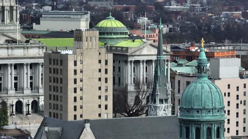 Pennsylvania state capitol building in Harrisburg Pennsylvania. Long aerial tilt up zoom reveal from historic church. Helicopter like motion.