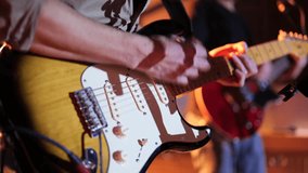 Video of a man playing the electric guitar during a concert, no faces shown, close up look 