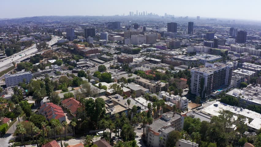 Descending aerial shot of apartments in Hollywood with Downtown Los Angeles in the background. 4K