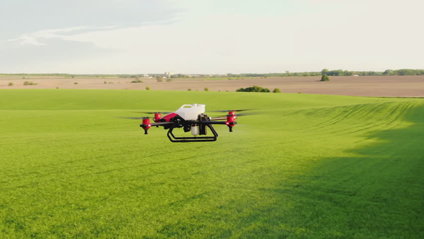 Agricultural drone for spraying fertilizers flies in the air over a green field. Innovations of smart agriculture, agro-industrial technologies. Aerial shot | Shutterstock HD Video #1101043583