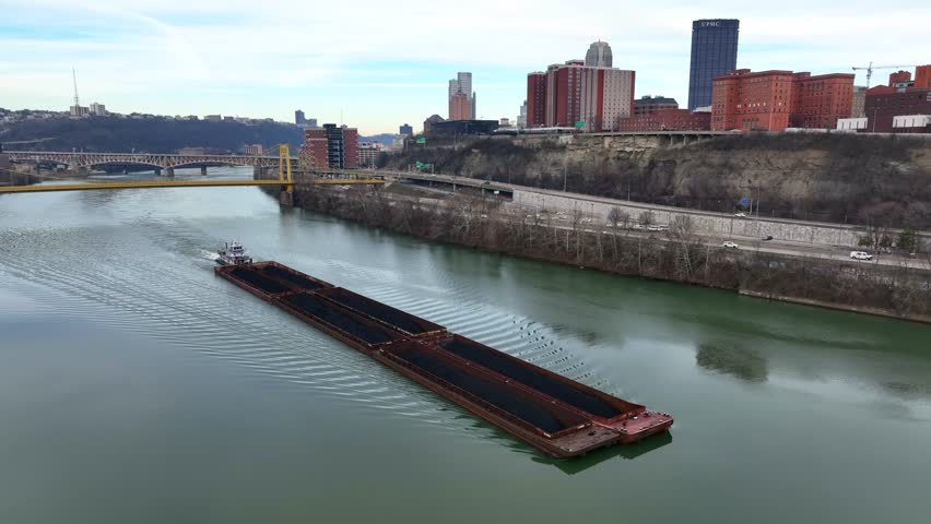 Aerial shot of barge on Monongahela River in Pittsburgh, Pennsylvania. Ship carrying coal with Pittsburgh, Pennsylvania skyline in background.