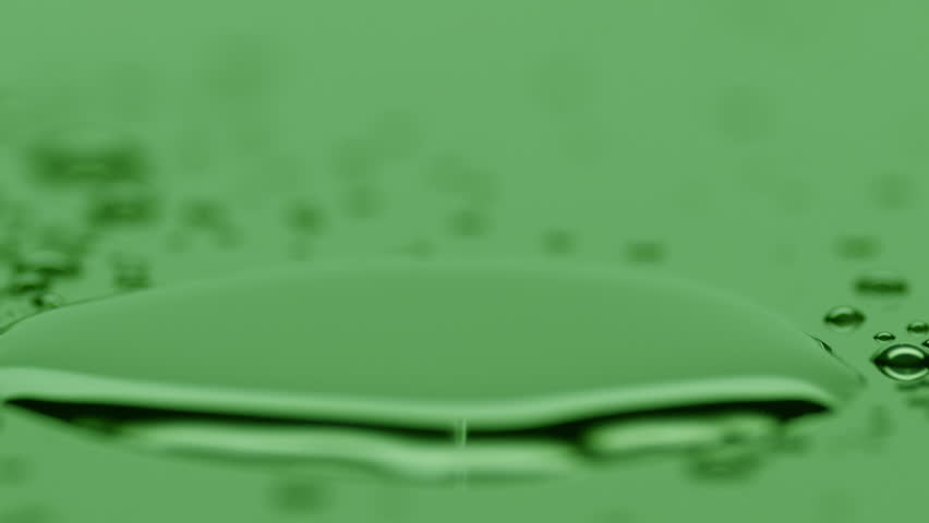 Macro jib shot of small water drop drips on big one splashing on green background | Skin hydrating concept | Shutterstock HD Video #1101045765