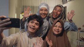Happy Asian muslim family greeting celebrate long distance with cousin use cell phone video call online Ramadan dinner together at home. Two generation celebration of Eid al-Fitr togetherness at home. - Powered by Shutterstock - Get 15% off with code: PIKWIZARD15