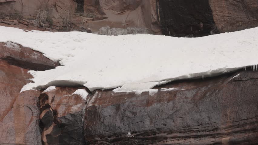 The waterfall at the Temple of Sinawava in Zion Nat. park, Utah has a bank of snow collected on the rock ledge. Occasionally chunks of snow fall from above and hit this bank with a splash and a boom. 