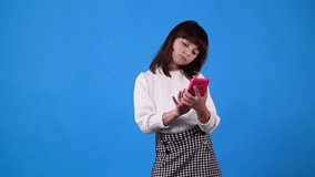 4k video of one young girl talking on the phone with someone over blue background.
