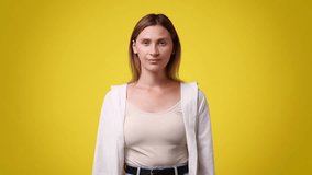4k slow motion video of one girl smiling and sends a kiss of air over yellow background.