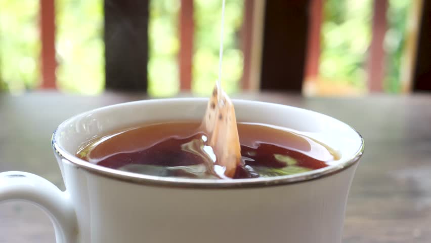 Dipping a teabag into a cup. | Shutterstock HD Video #1101054855