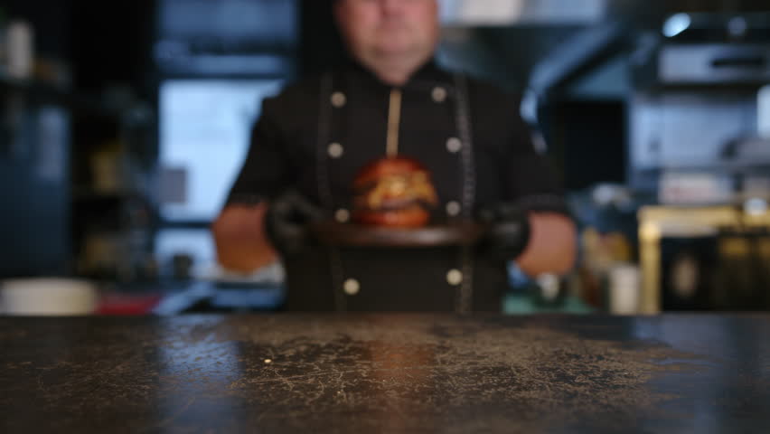 the chef puts a freshly prepared burger on the table. slow motion. High quality 4k footage Royalty-Free Stock Footage #1101061131