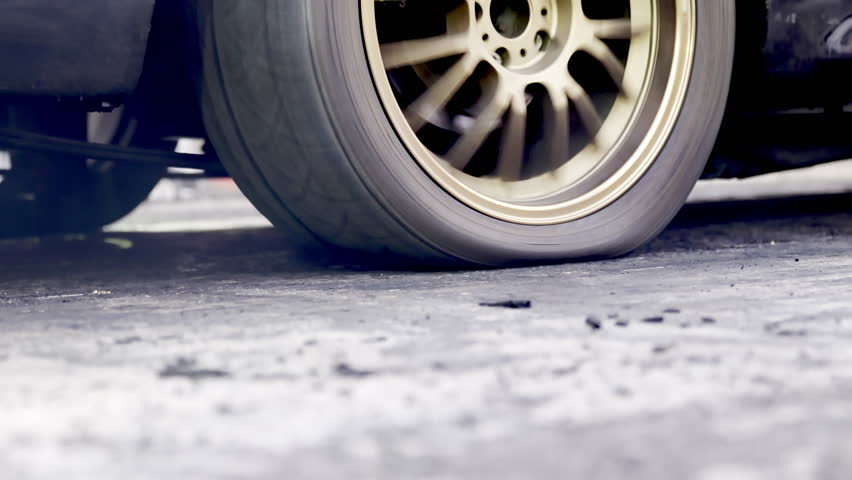 Drag racing car burning tire at starting line in race track