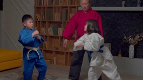 Motivated active elementary age taekwondo Asian fighters in uniform practicing sparring session under guidance of senior martial arts master, working out combat skills during contactless fight. - Powered by Shutterstock - Get 15% off with code: PIKWIZARD15
