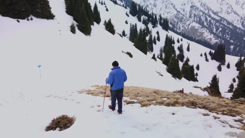 A man with trekking poles travels in the mountains.