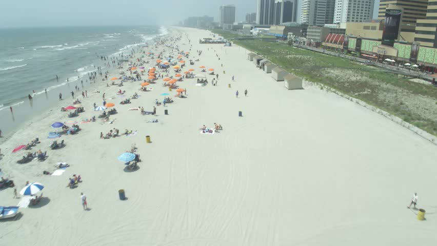 Aerial above white sand beach in Atlantic City, New jersey with tall skyscrapers boardwalk and beach goers