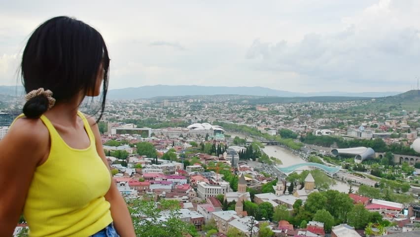 Panning view young caucasian woman stand on viewpoint enjoy scenic Tbilisi city panorama from Narikala fortress in summer. Travel in Georgia, caucasus | Shutterstock HD Video #1101066497
