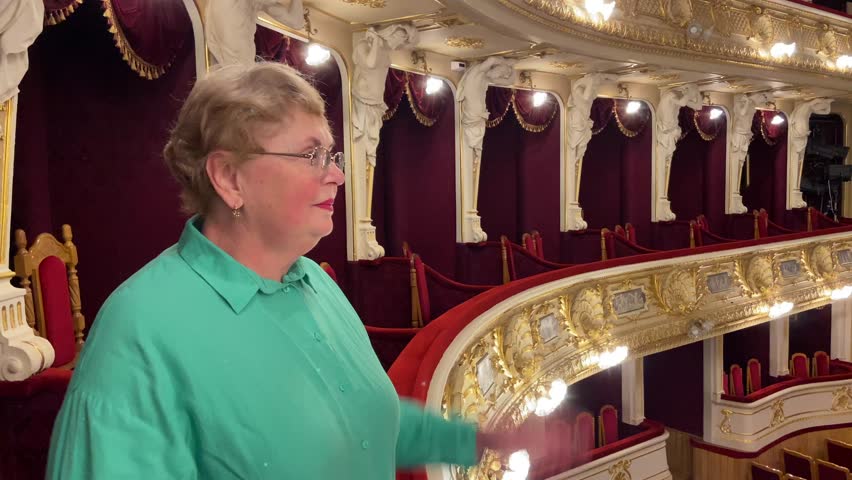 Senior woman applauding and  watching ballet performance in theater hall, woman claps and enjoy