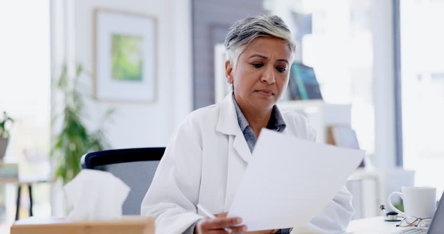 Yawn, tired and senior doctor with documents at desk with fatigue, sleepy and exhausted in hospital. Healthcare, clinic and bored woman medical worker reading paperwork, prescription or insurance Royalty-Free Stock Footage #1101072885