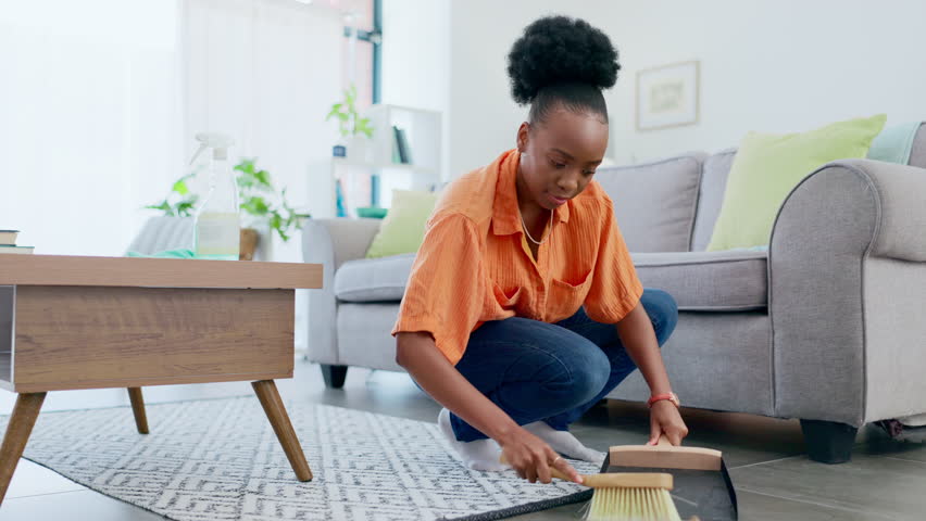 Sweeping, cleaning and black woman in home living room to remove dust or dirt on floor for health and wellness. Service, maid and female housekeeper or cleaner with chores for hygiene maintenance. | Shutterstock HD Video #1101073053