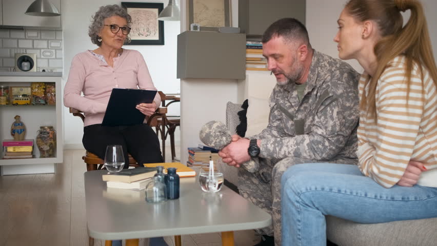 Soldier with his wife having therapy meeting with senior female psychologist.
