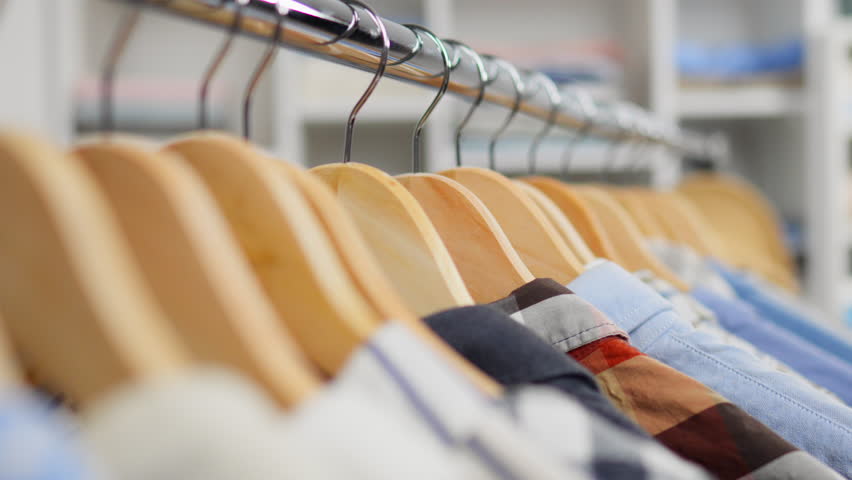 Organized interior, beautiful different clothes hanging on wooden hangers. Stack of seasonal clothes, camera in motion assortment of clothes for buying indoors, retail
 | Shutterstock HD Video #1101075039