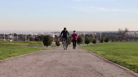 mature couple does sports in the park, she running and he with a bicycle - retired healthy life -
