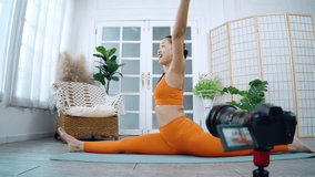Asian women doing yoga while shooting a social media video, Blogging for at-home online learning.  38-year-old woman stretching in Janu Sirsasana or Head to Knee Pose, Seated forward bend pose