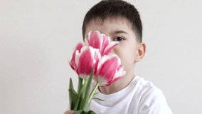 cute kid holding bouquet of tulips ,box gift sitting on bed giving,gift for mother march 8th women international day.child smelling tulip holding on nose.tulips in pants with phone calling spring - Powered by Shutterstock - Get 15% off with code: PIKWIZARD15
