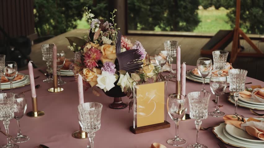 Beautiful wedding table decor, all decorated in pastel pink colors. Festive served with candles, plates, glasses on the table, camera moving slow motion. | Shutterstock HD Video #1101078089