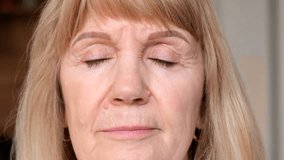 Close-up portrait of a beautiful elderly woman who opens her eyes. High quality 4k video