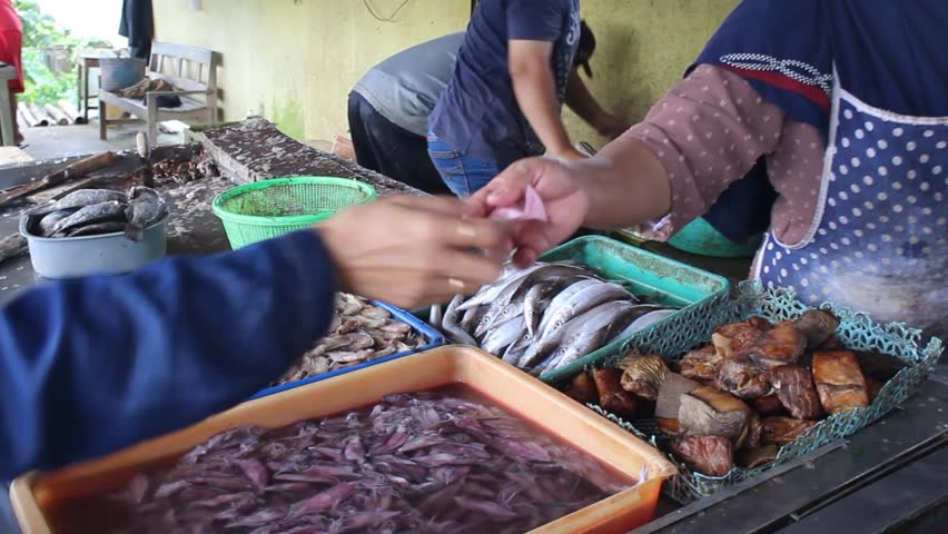 The fish seller in the market is making a cash payment process with the buyer
