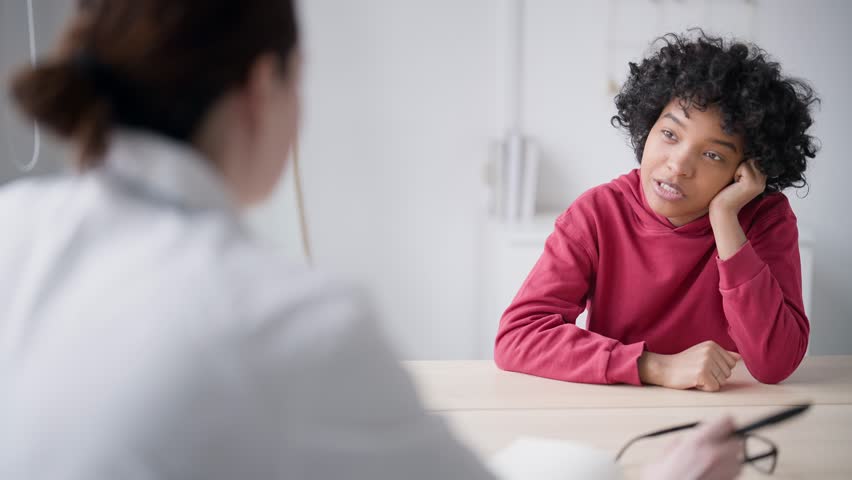 Young african american woman patient talk, ask questions at reception doctor. Female doctor listens and answers. Consultation at clinic cabinet. Healthy lifestyle. Concept medical health care help. | Shutterstock HD Video #1101082535
