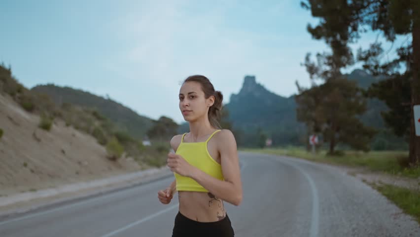 Slow motion portrait of Young Athlete Woman Running Fast down Road, Training Hard, Getting Ready for Race Competition or Marathon. Fit Girl in Black shorts Jogging At Dawn along Green Fields. | Shutterstock HD Video #1101092241