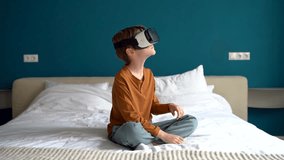 Child boy wearing virtual reality headset interacting with digital world, curious kid exploring universe with vr, sitting on bed at home. Children and immersive learning experience, metaverse for kids