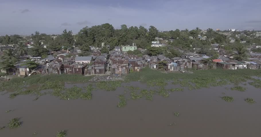 View of the Sea with Aquatic Plants Very Close to the Shore Next to Old and Poor Houses Built with the Remains of Construction Material due to the Losses Caused by the Hurricanes - Shot in Log