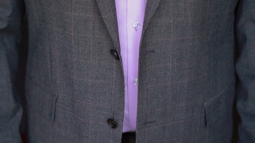 Young male businessman or groom on a wedding day in a purple shirt and gray suit. A man fastens a button on his jacket. | Shutterstock HD Video #1101097317