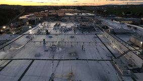 Sunset over factory and warehouse in America. Aerial shot of steam and HVAC units on rooftop of commercial building. - Powered by Shutterstock - Get 15% off with code: PIKWIZARD15