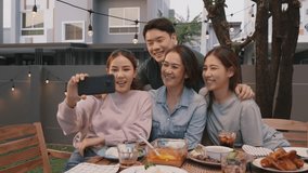 Young adult asia people hug love care for mom taking photo selfie video on mobile phone camera at home picnic dining fun night party dine table. Relax older mum smile enjoy warm time happy hour meal.