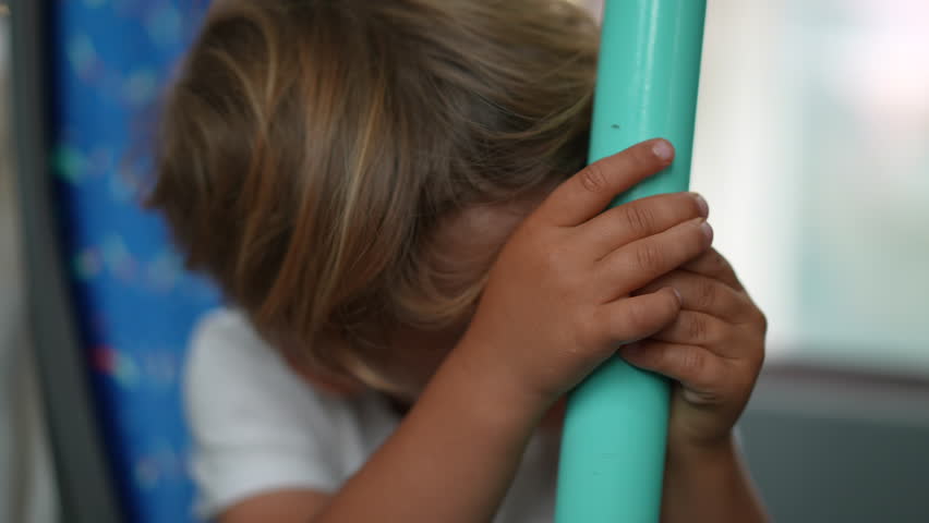Child leaning on metal bar inside tram city transportation. One small boy hand holding into pole traveling by bus feeling boredom