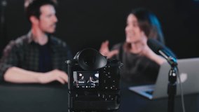 Man and woman creators broadcasting live product review on podcast station, streaming internet vlog and chatting for social media channel. Focus on foreground, Behind the scenes, 4k video, horizontal.